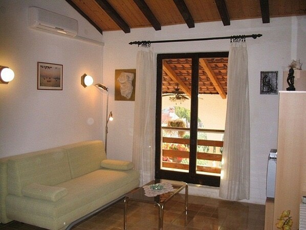 A living room with a sofa, a coffee table, a ceiling fan, and a window with curtains. - Apartments Matohanac (Fazana)