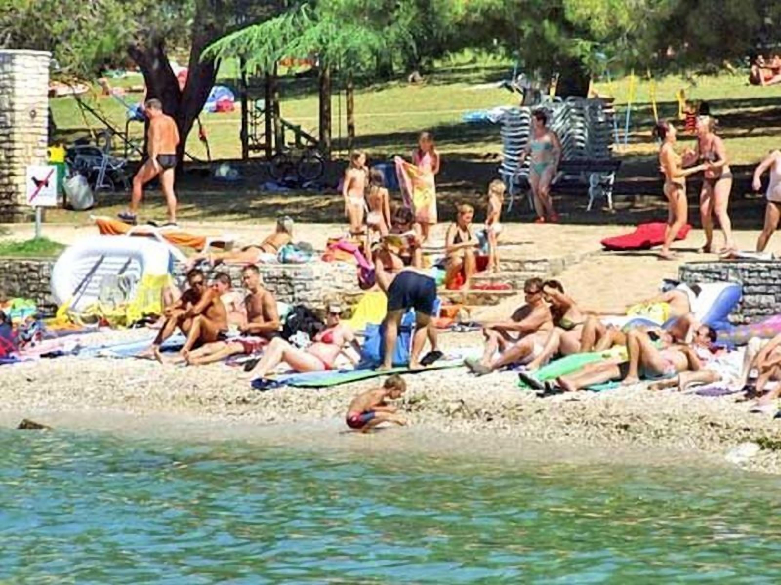 Una spiaggia affollata con persone che prendono il sole e nuotano.