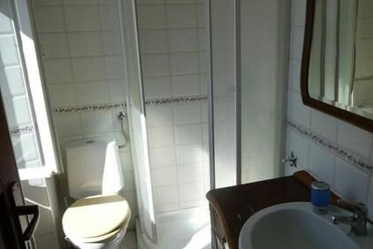 A bathroom with a toilet, shower, and sink.