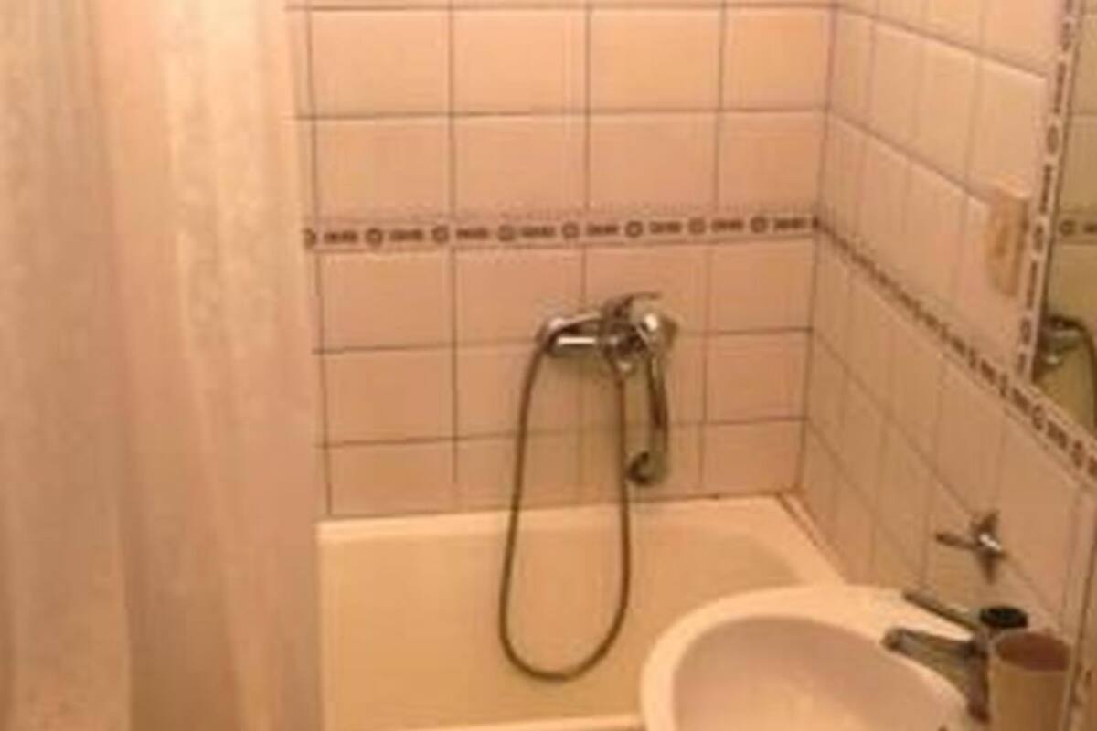 A small bathroom with a bathtub, sink, and tiled walls.