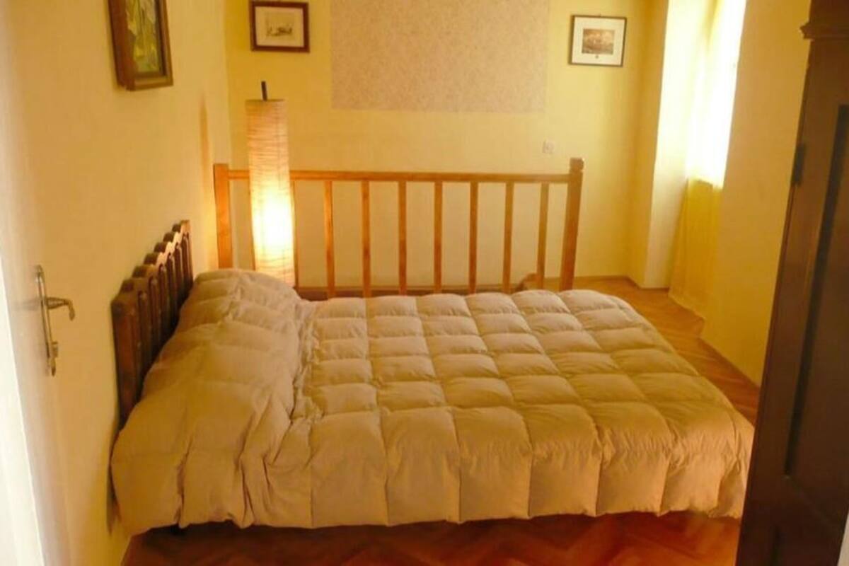 A bedroom with a wooden bed frame, a headboard, and a window with curtains.