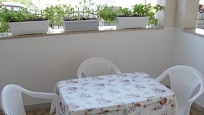 En terrasse med et bord og stole, omkranset af krukker med planter.