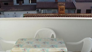 En balkon med et bord og fire stole, dækket med en blomstret dug.