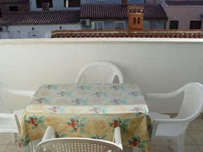 A balcony with a table and four chairs, covered with a floral tablecloth. - Apartment Mladen (Pula)