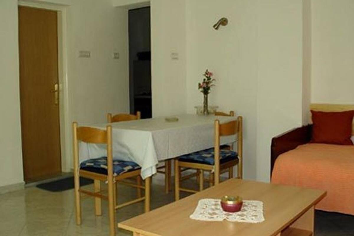 A small, simple room with a wooden table, two chairs, a sofa, and a door.