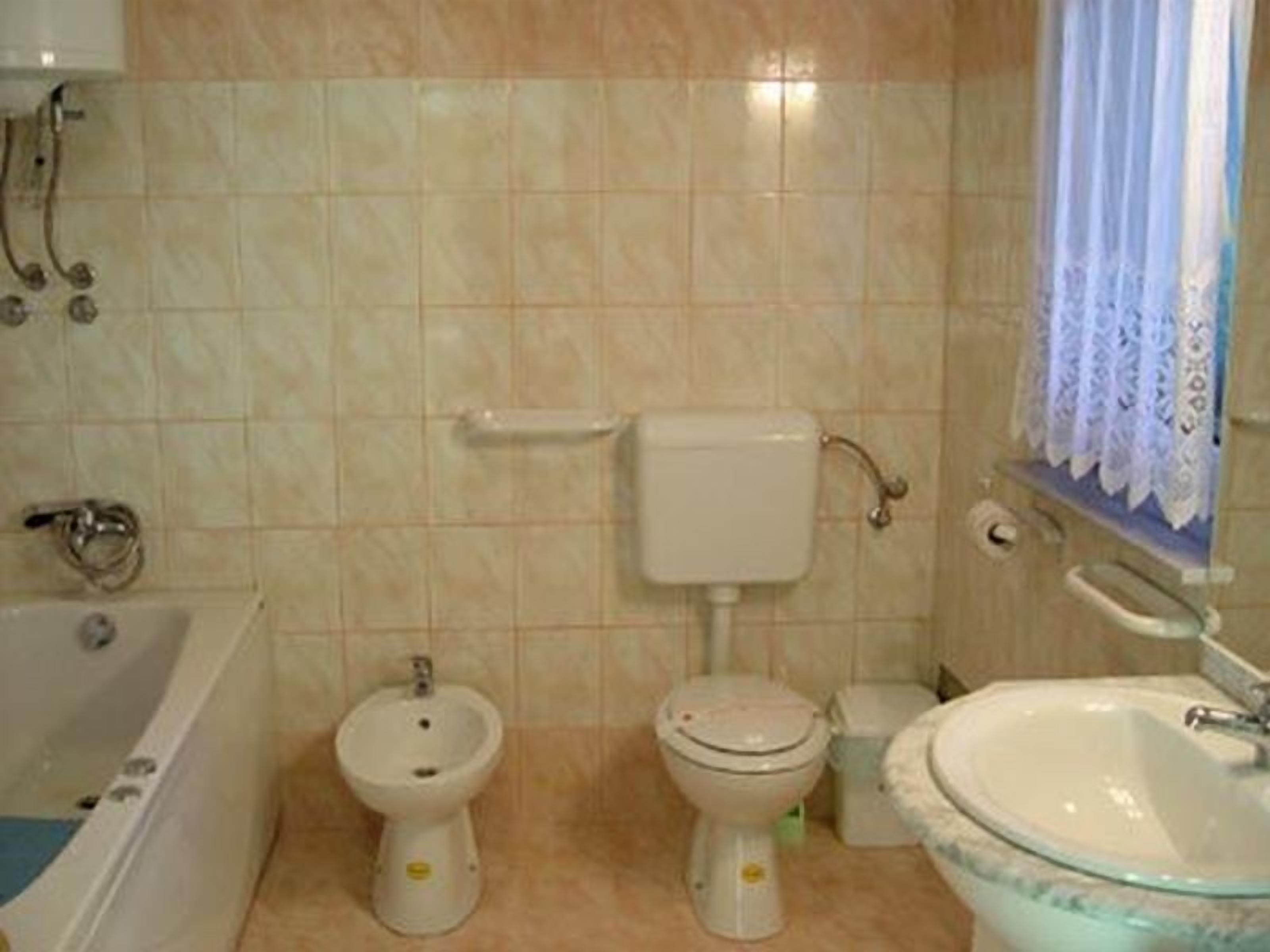 A bathroom with a bathtub, two toilets, a bidet, and a sink.