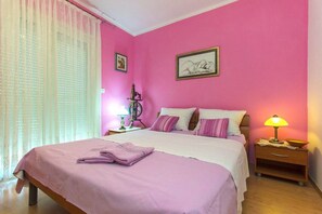 Une chambre à coucher avec un lit, une table de chevet, une lampe et deux tableaux encadrés accrochés au mur.
