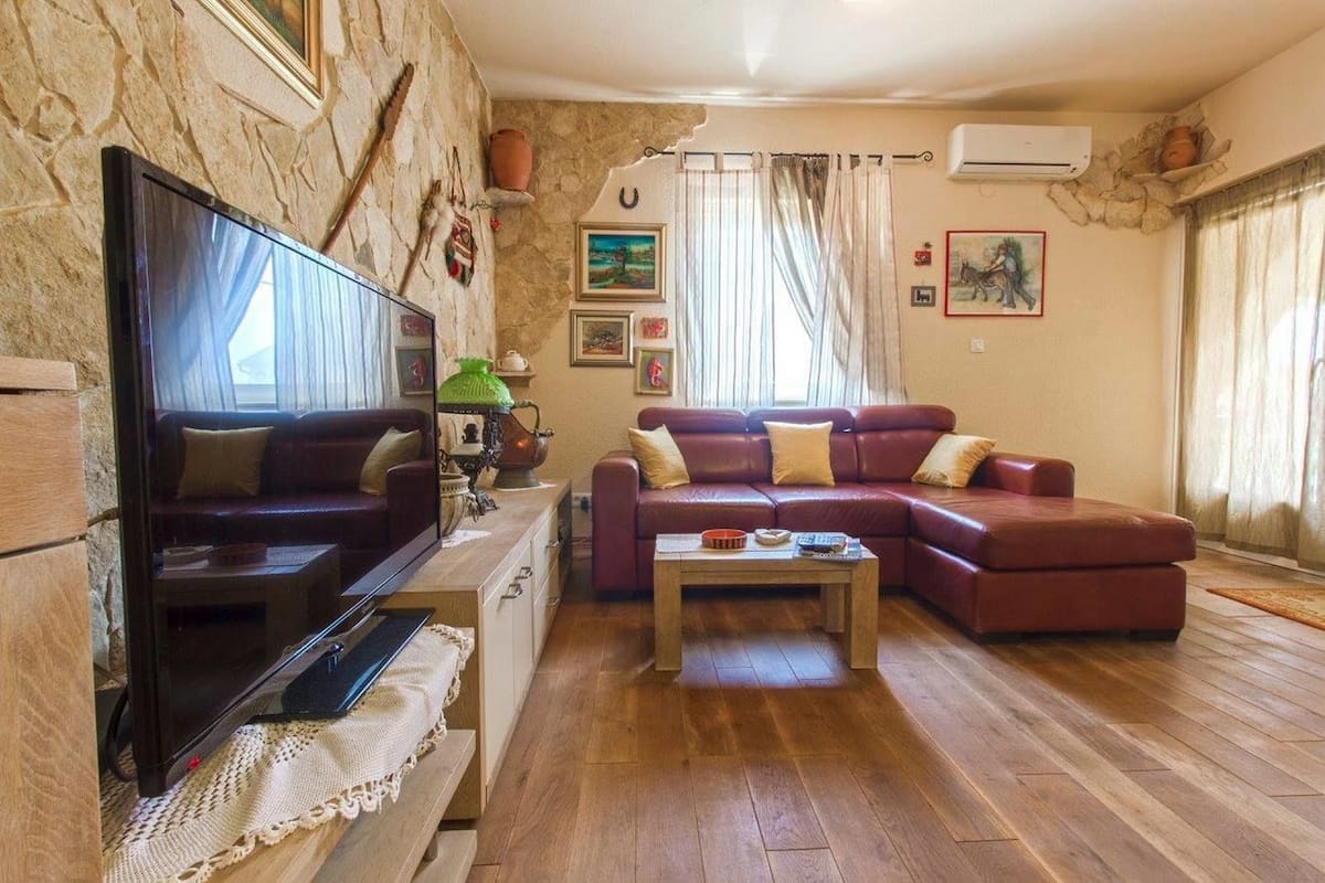 Ένα σαλόνι με τηλεόραση, έναν καναπέ, ένα τραπεζάκι σαλονιού και ένα τζάκι.