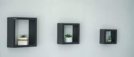 Three wall-mounted planters of varying sizes, each containing a plant.