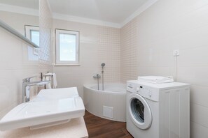 Un bagno moderno con una vasca, una lavatrice e un water.