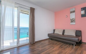 Una stanza con una porta vetrata scorrevole che dà su un balcone con vista sul mare.