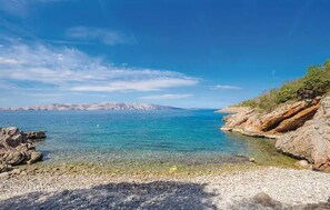 A coastal landscape with clear waters, rocky terrain, and distant mountains. - Apartments Marinko (Senj)