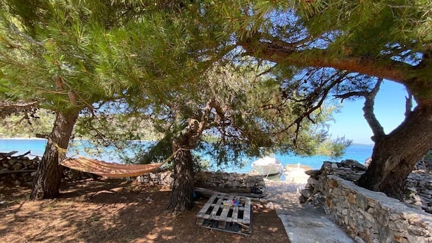 A hammock under a pine tree by a stone wall and a dock. - House Kornati Robinzon (Murter-Kornati)