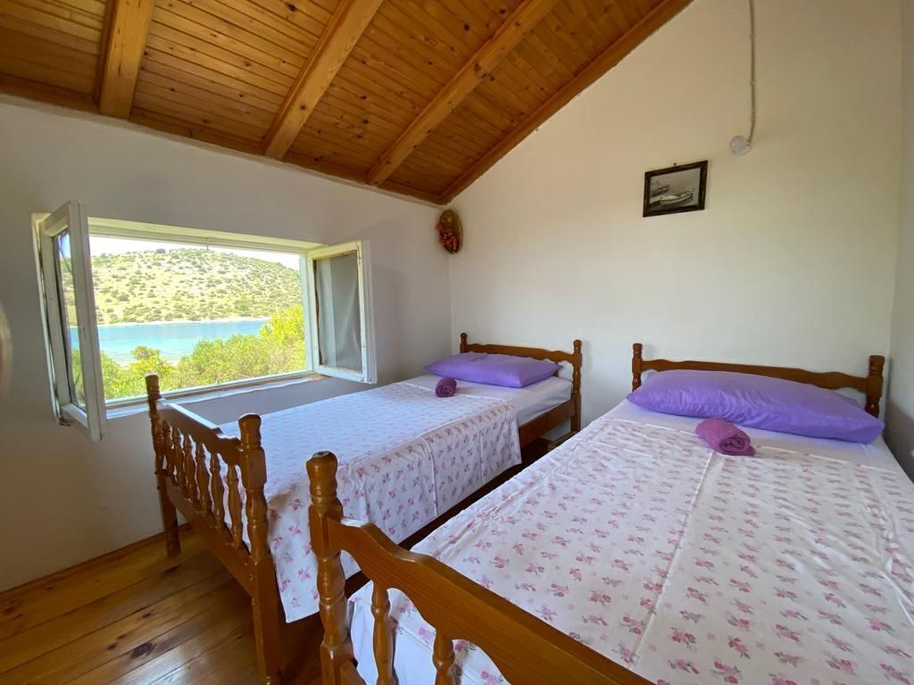 A bedroom with two wooden beds, a window with a view of a hillside, and a wooden ceiling.
