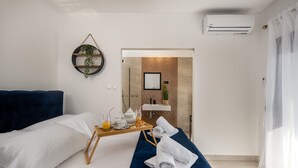 A hotel room with a bed, a breakfast tray, a towel, a wall-mounted air conditioner, and a view of a brick wall and a sink. - Apartment Villa Rebeka (Opatija)