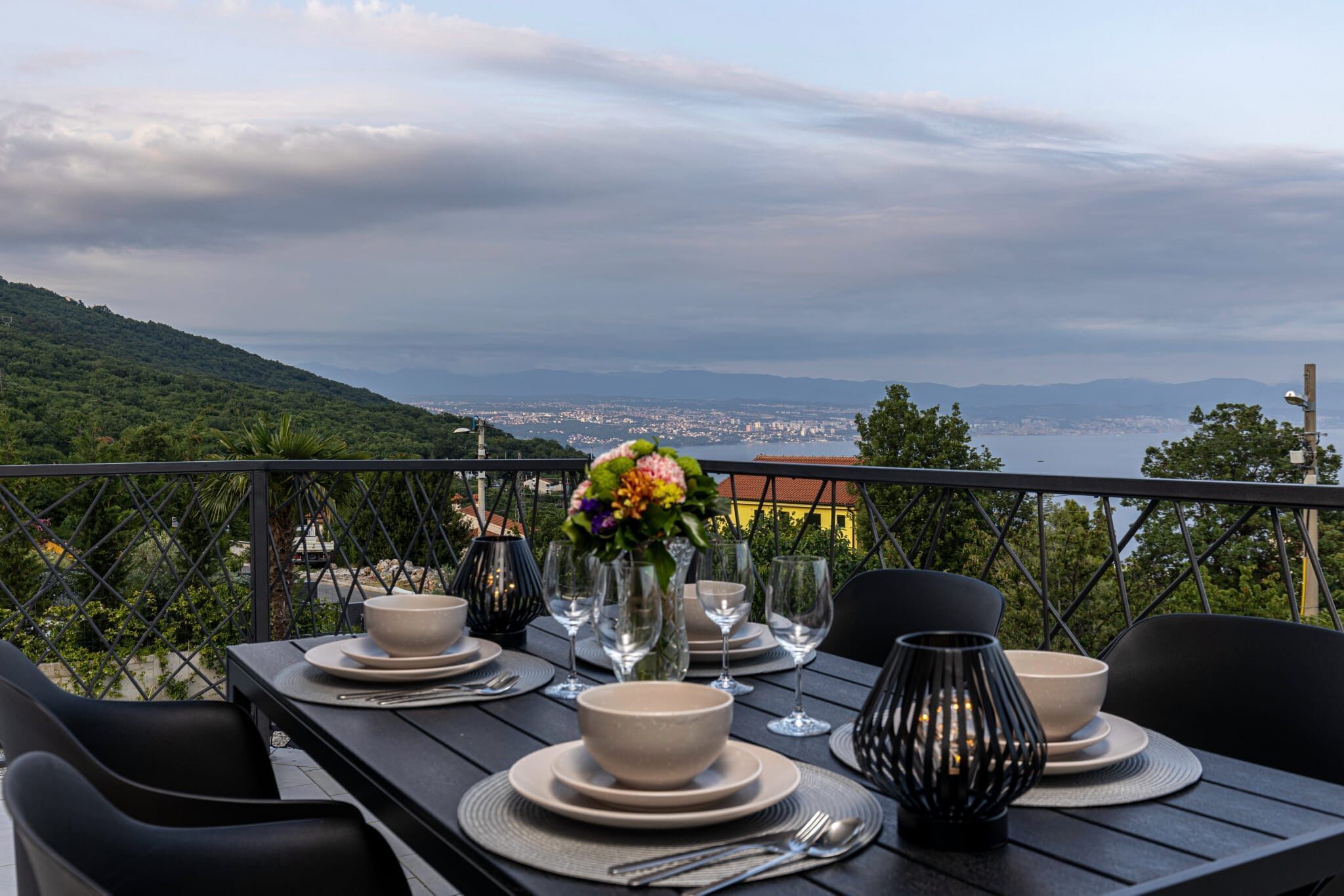 A table set for dining with a view of a city and mountains in the background.