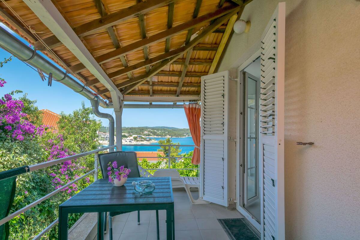 A balcony with a table, chairs, and a view of the sea.