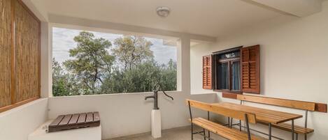 A balcony with a wooden bench, a window with shutters, and a water tap.