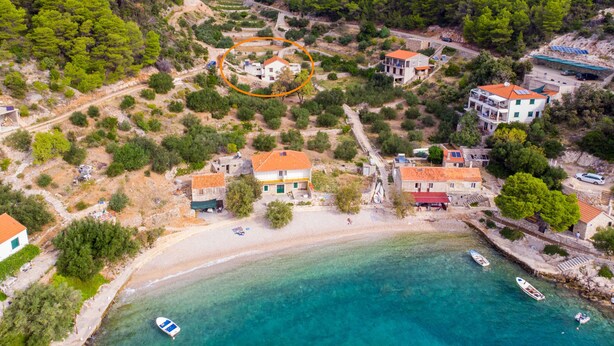 Luftaufnahme einer Küstenlandschaft mit Gebäuden, einem Strand und Booten.