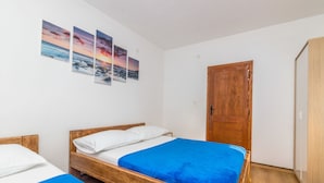 Ein Schlafzimmer mit zwei Einzelbetten, Holz-Kopfteilen, einem Holzschrank und einer Wand mit drei gerahmten Bildern.