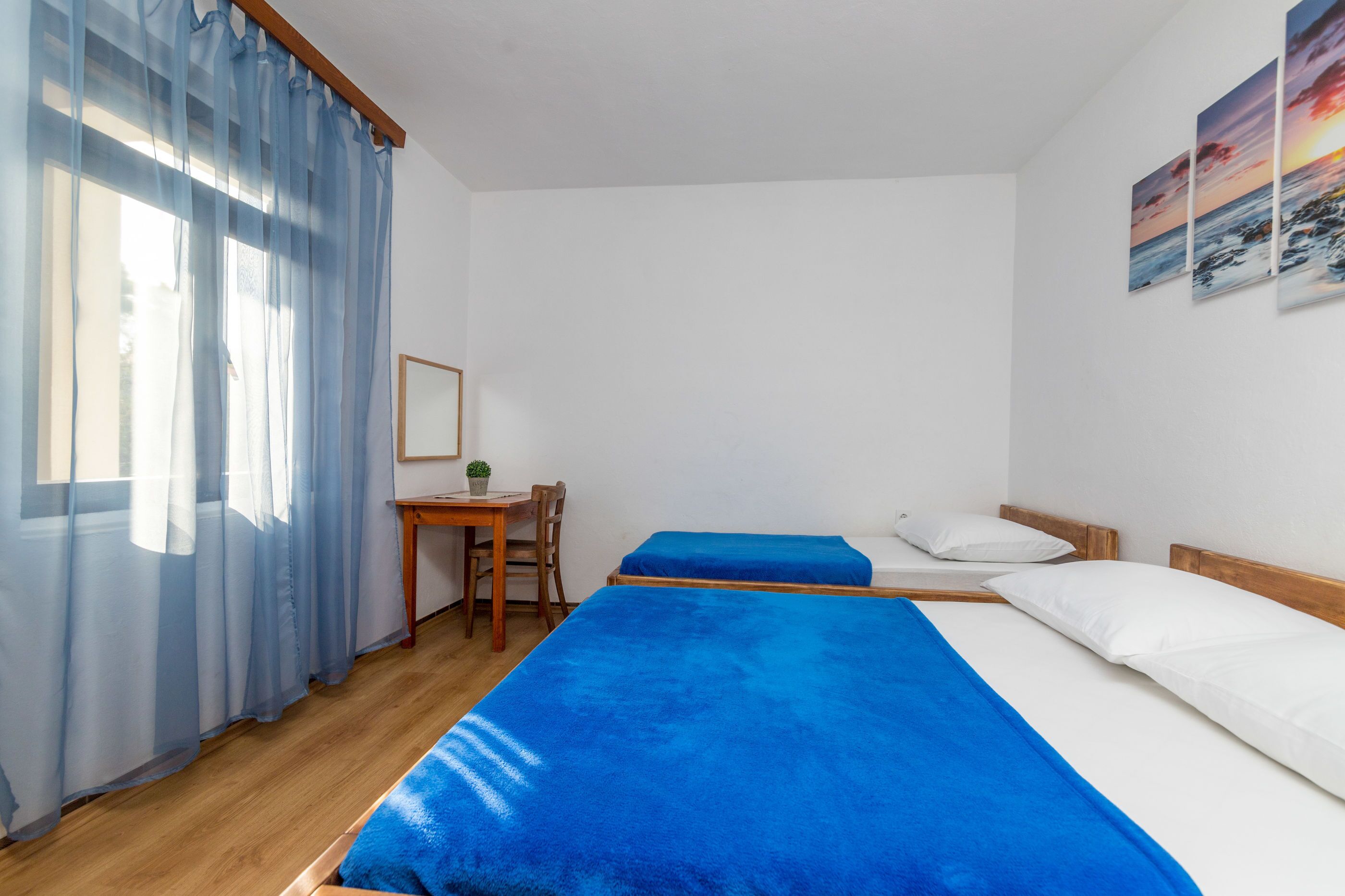 A room with two beds, a desk, and a chair.