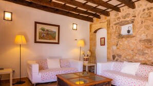 Uma sala de estar acolhedora com dois sofás brancos, uma mesa de centro de vidro e uma parede de pedra.