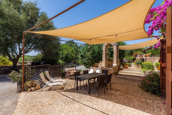 An outdoor patio with a table and chairs, a canopy, and a stone pathway.