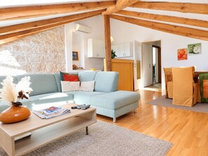 A modern living room with a light blue sofa, a wooden coffee table, and a stone wall. - Apartments Radomir (Fazana)