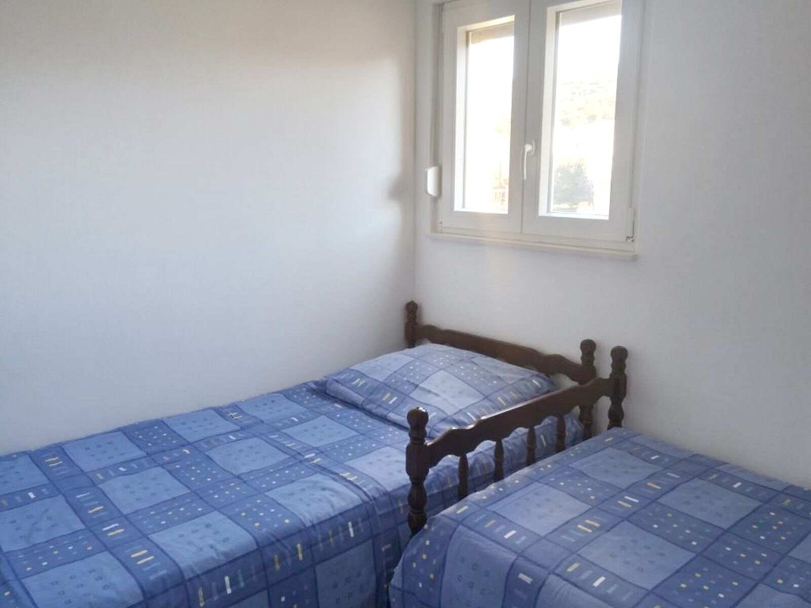 A small, single-bed room with a wooden headboard and a window.