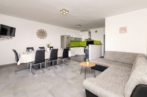 A modern living space with a dining area, kitchen, and seating area. - Apartments and Room Lotus (Tribunj)
