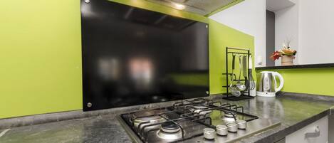 A kitchen with a gas stove, a kettle, and a coffee maker on the counter.