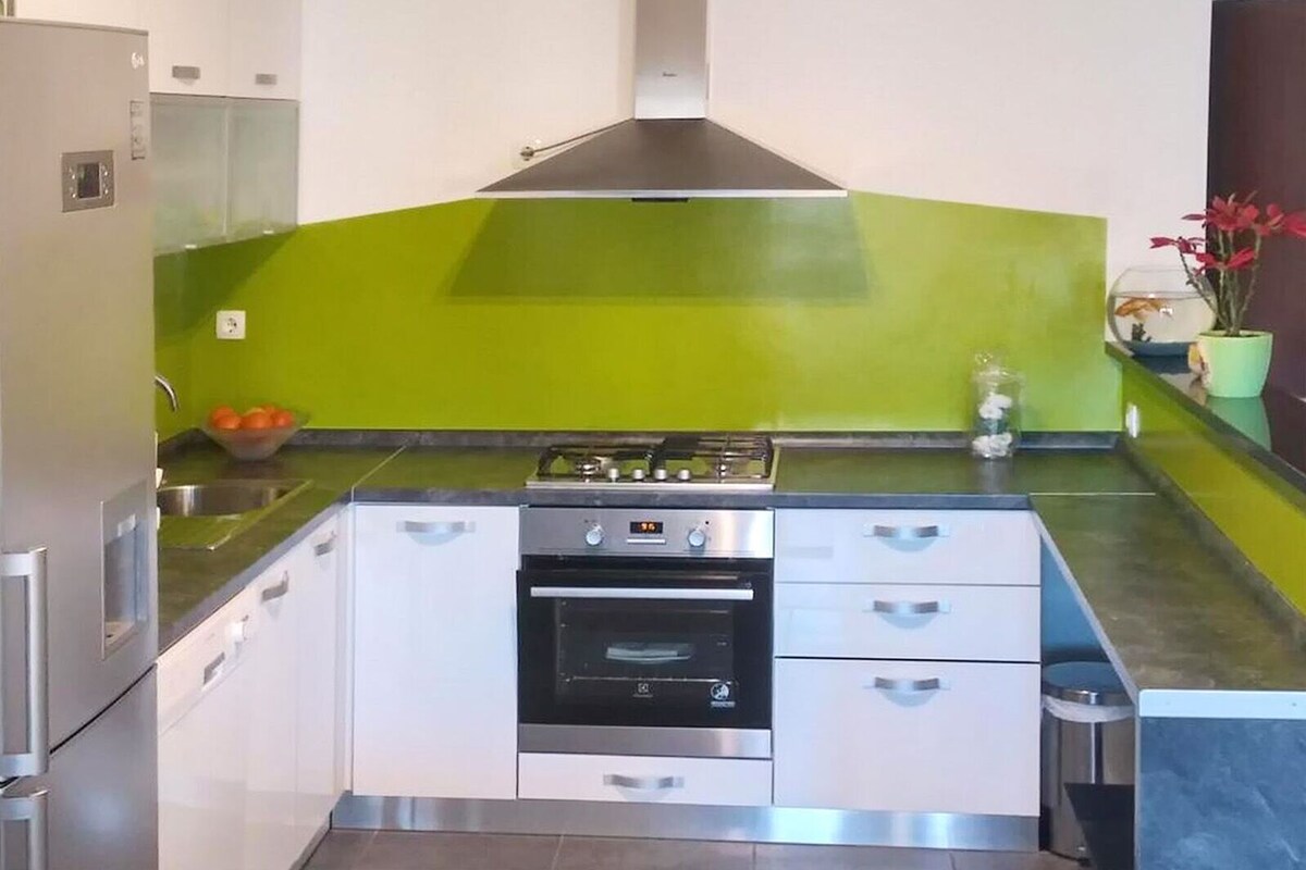 A compact kitchen with a gas stove, oven, and a green accent wall.