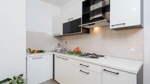 Eine moderne Küche mit weißen Schränken, einem Gasherd und einer Spüle.