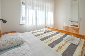 A bedroom with a bed, a nightstand, a dresser, and a window with sheer curtains. - House Rovana (Jasenice)