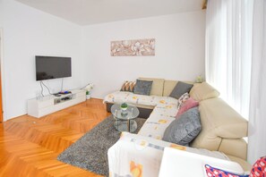 A modern living room with a sofa, a coffee table, a flat-screen TV, and a white console unit. - House Rovana (Jasenice)