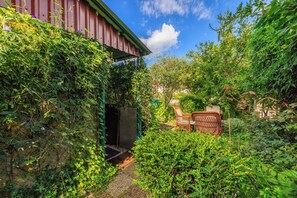 A garden with a wooden fence, a chair, and a small building. - Apartments Divano (Crikvenica)