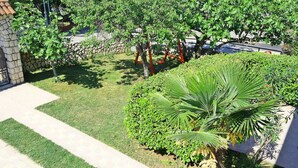Un jardín bien cuidado con un muro de piedra, una palmera y diversos arbustos.