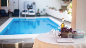 A poolside table with a bottle, glasses, and a decorative box. - Apartments and Room Agiss With Pool (Vodice)