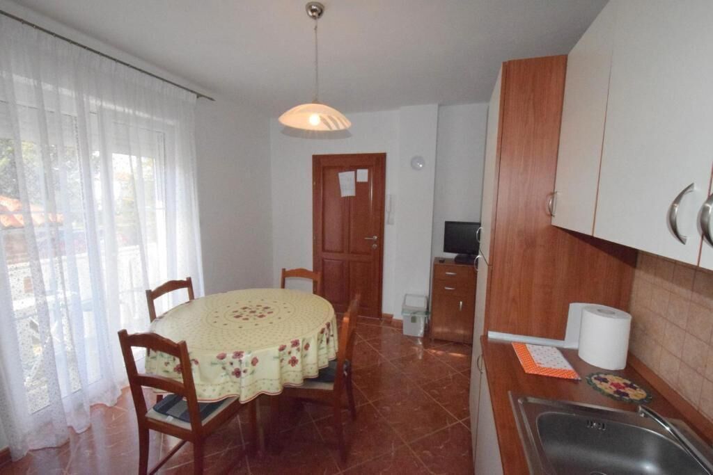 Cocina compacta con mesa, sillas, pileta y alacenas.