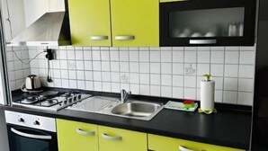 A kitchen with yellow cabinets, a black countertop, a stainless steel sink, and a stove. - Apartments Vladimir (Malinska-Dubasnica)