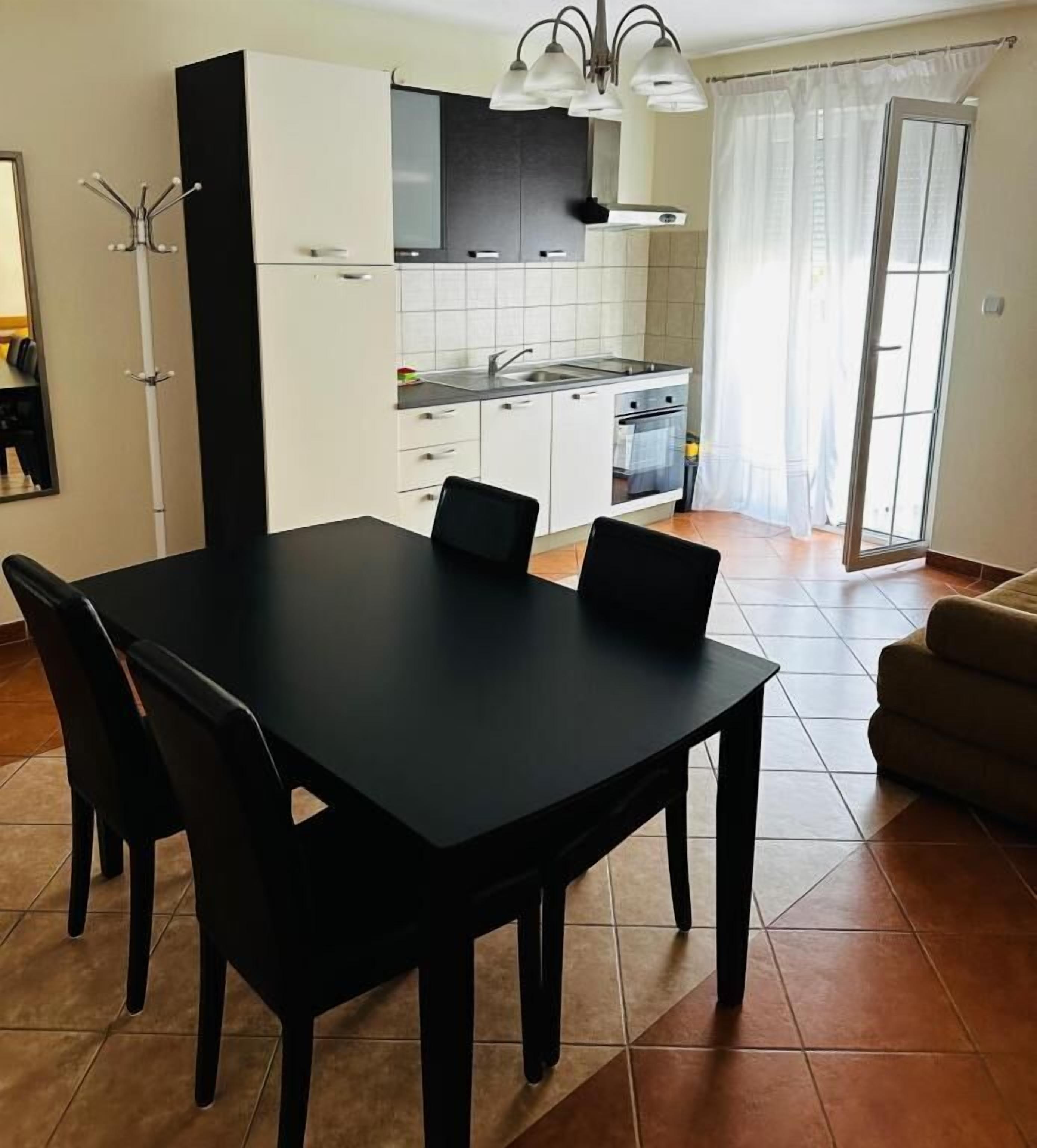 A compact kitchen with a dining table, chairs, and a sofa.
