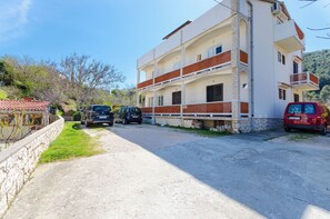 En byggnad med flera våningar, vit fasad och röda detaljer, med balkonger och en grund av sten.