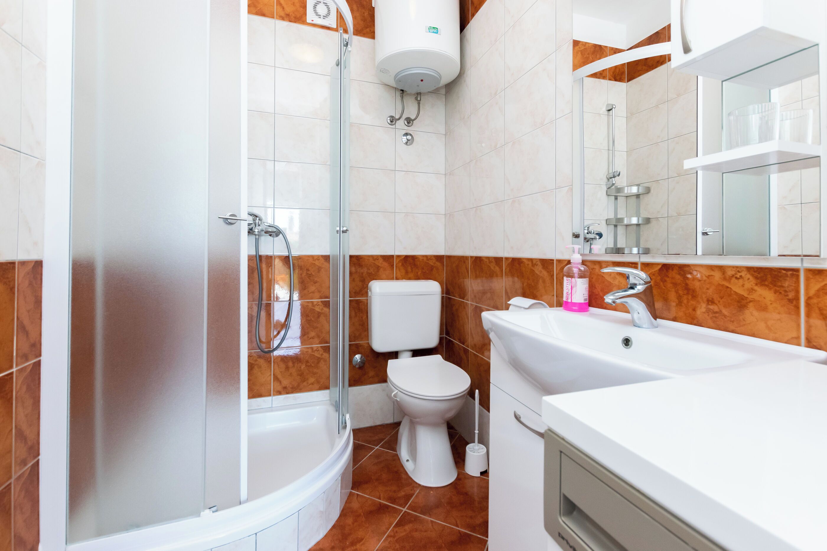 A modern bathroom with a glass-enclosed shower, a white toilet, and a sink with a mirror above it.