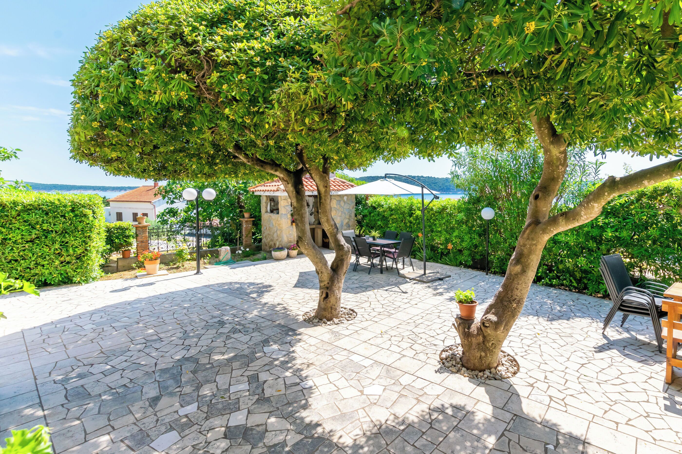 A patio with stone flooring, outdoor furniture, and trees.