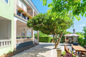 Un patio con suelo de piedra, mobiliario exterior y un árbol.