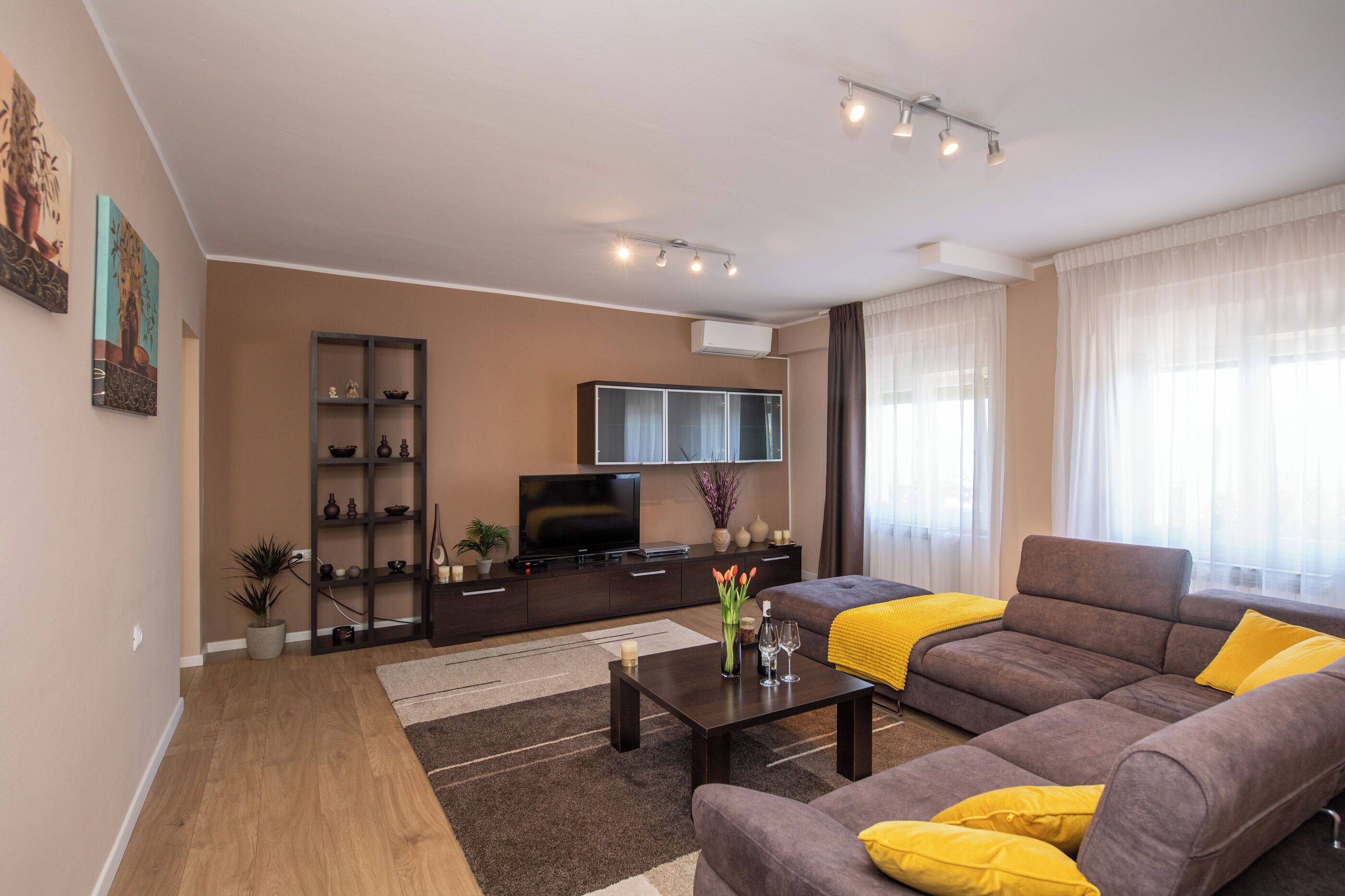 A modern living room with a sofa, coffee table, TV, and decorative items.