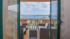 Een balkon met rieten meubels en uitzicht op zee.