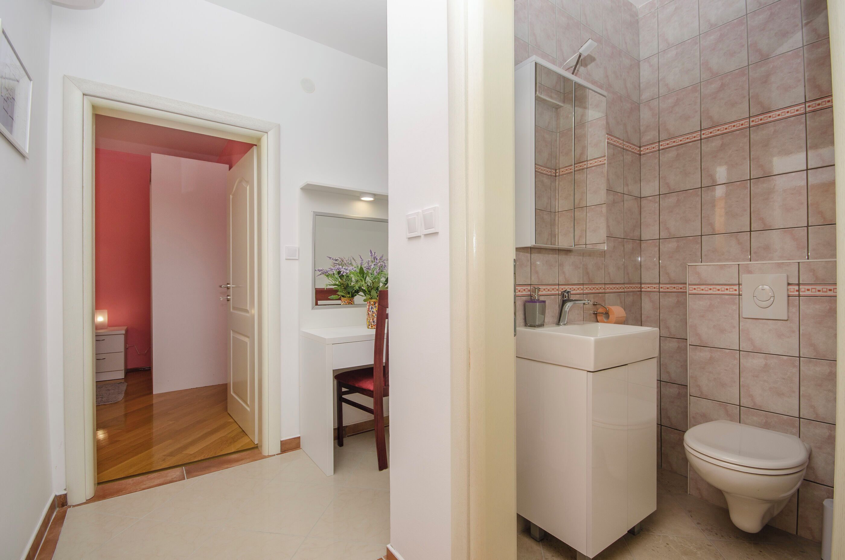 A hallway leading to a bathroom with a shower, a sink, and a toilet.