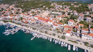 An aerial view of a coastal town with numerous buildings, a marina with boats, and a clear blue sky. - Apartments Villa AS Jezera (Tisno)