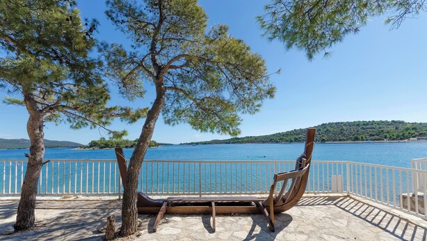 A bench overlooking a body of water with a view of a distant hill. - Apartments Villa AS Jezera (Tisno)